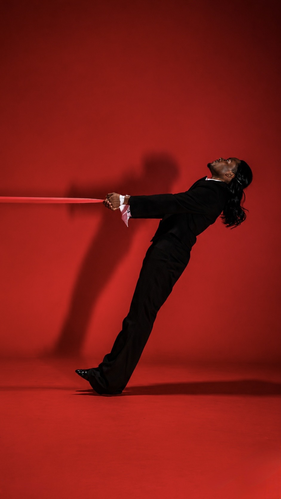 TERRANCE DEAN leaning backward while holding a red ribbon