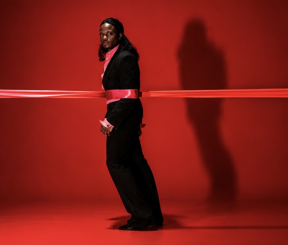 TERRANCE DEAN standing with a red ribbon stretched across the studio