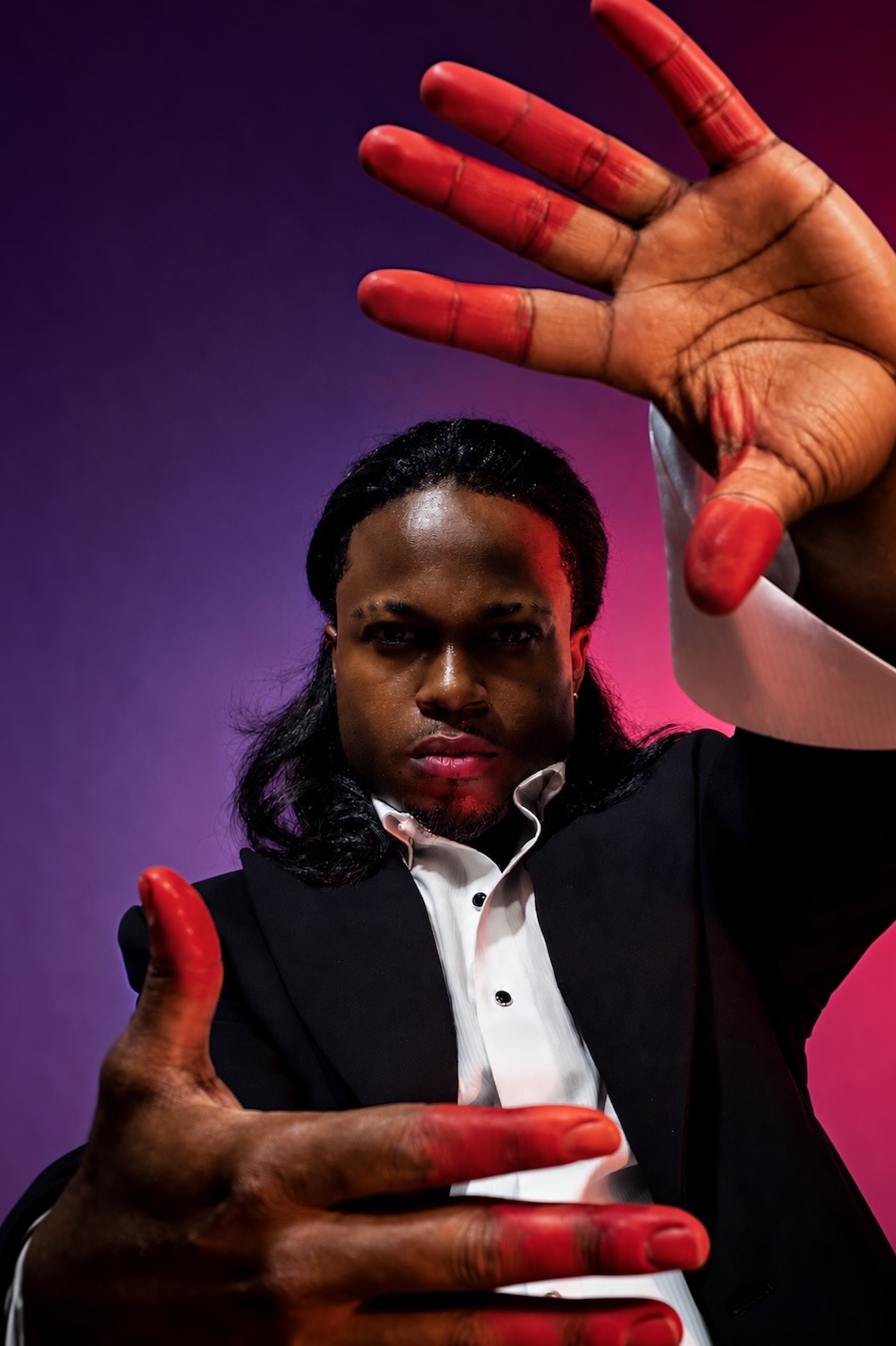 TERRANCE DEAN framing the camera with hands in violet light