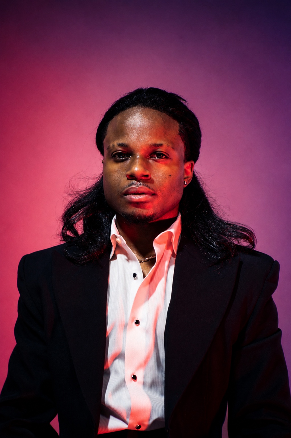 TERRANCE DEAN in a black suit under violet and crimson light